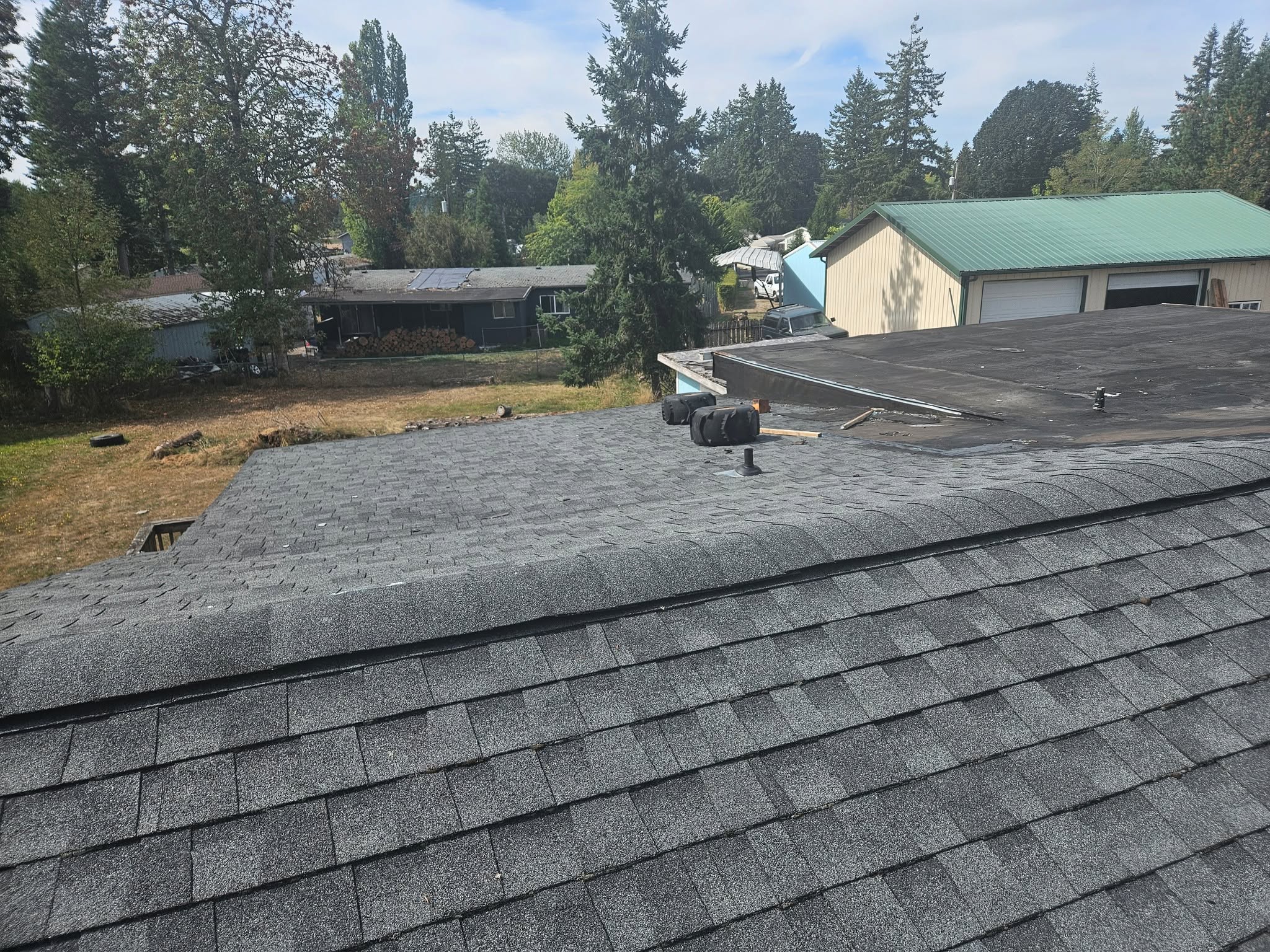 Newly installed charcoal architectural shingles looking down from the ridge