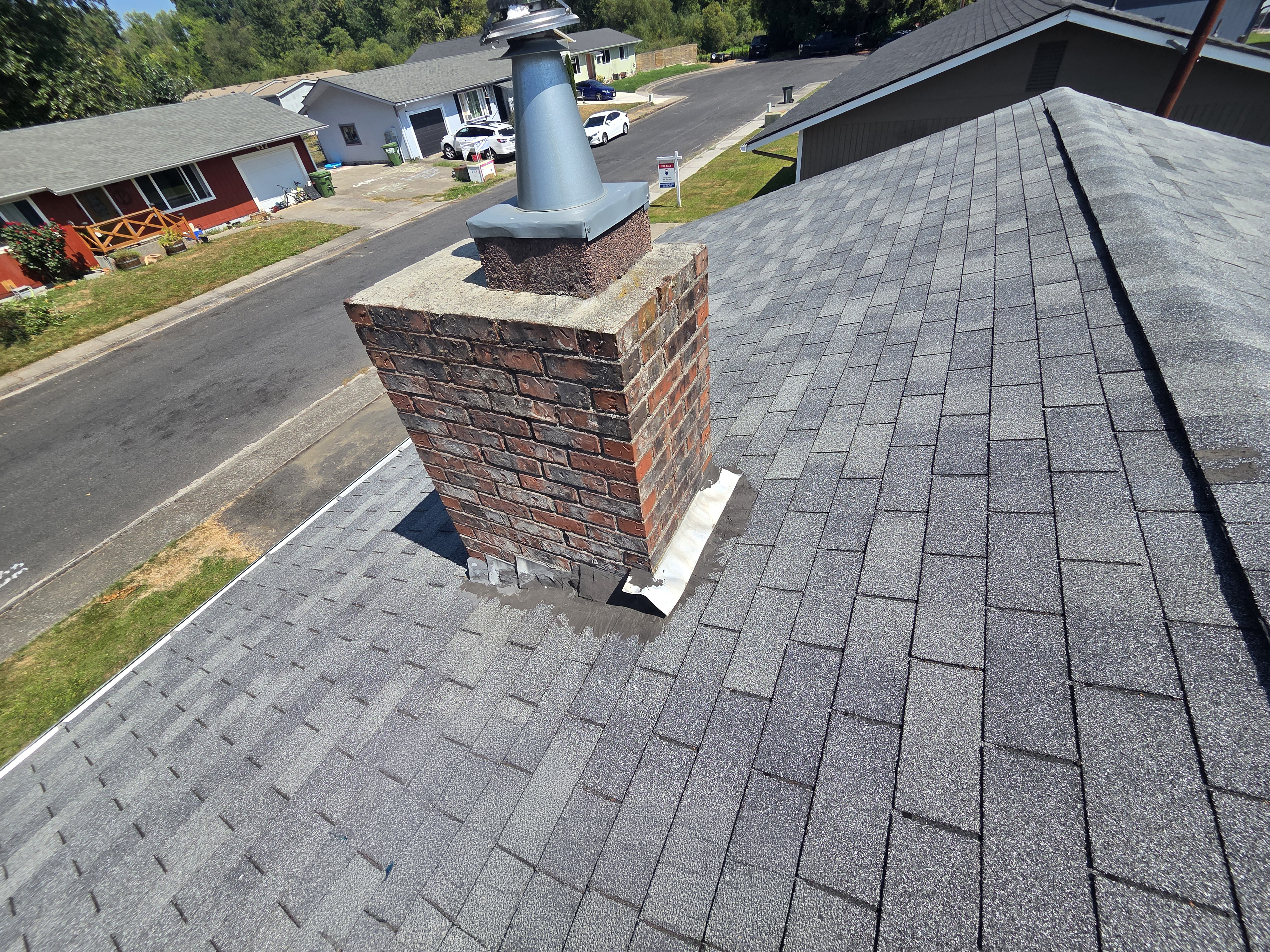 Existing shingles and chimney flashing before the new roof