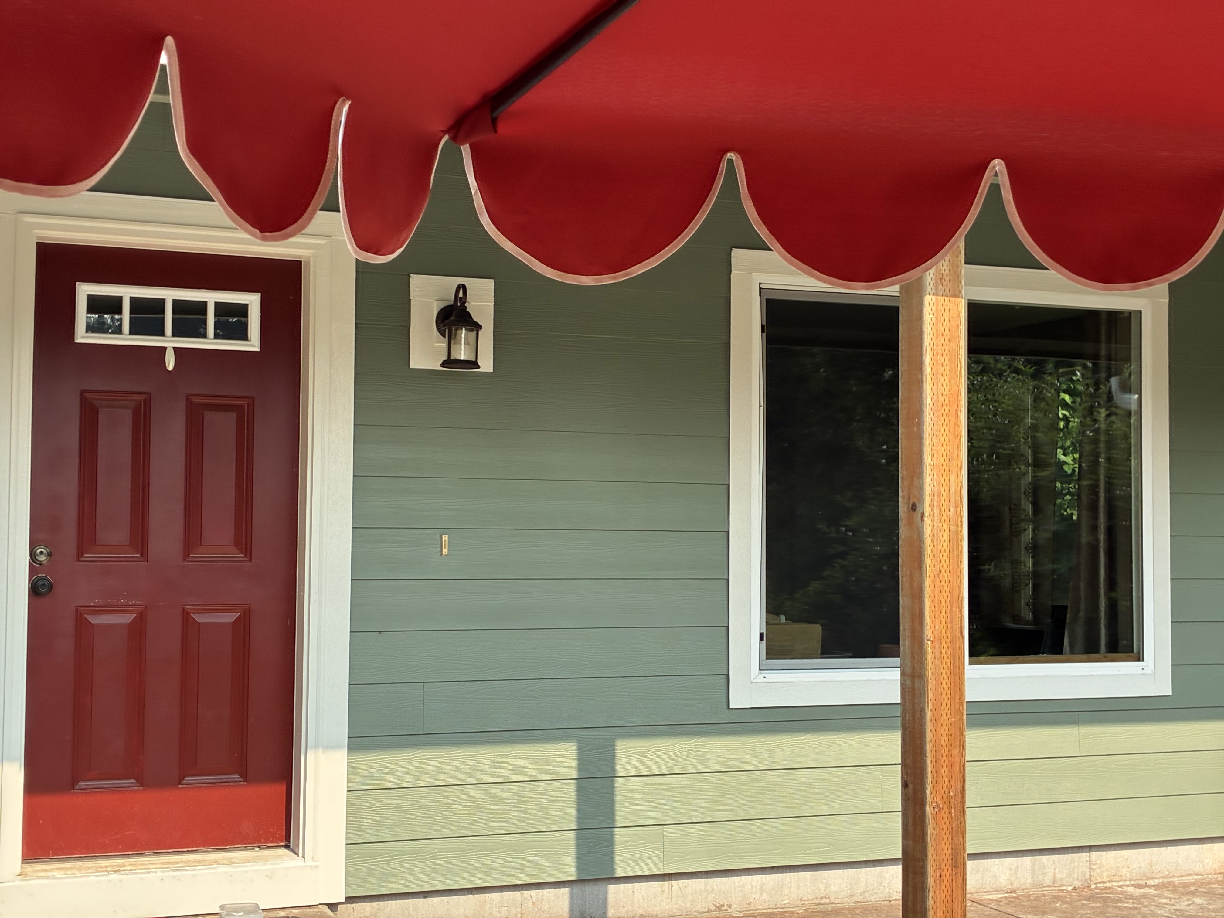 Sage green siding and white trim at a residential entry after TK Construction finished the exterior
