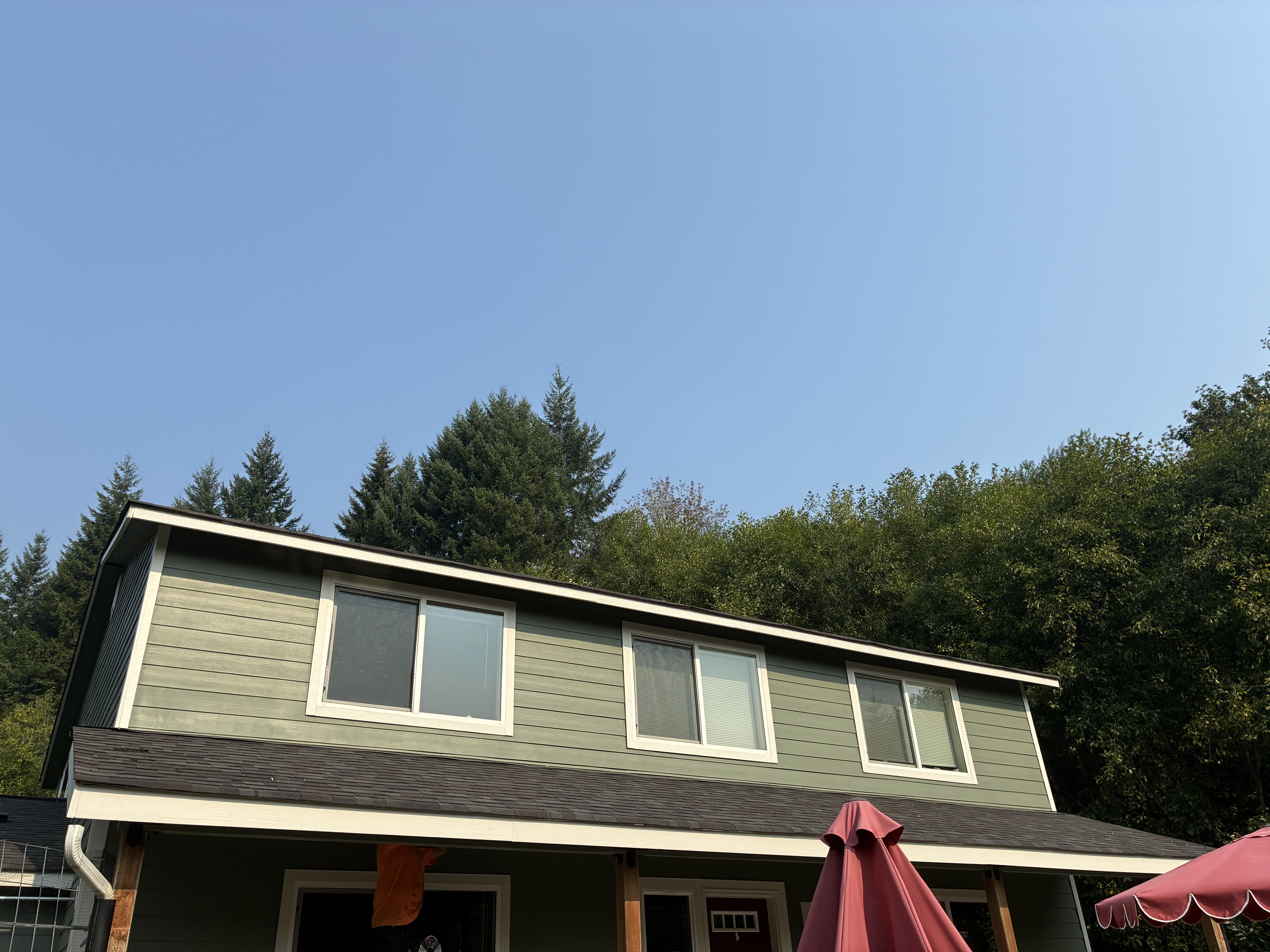 Sage green lap siding, white trim, and new shingles after TK Construction finished the exterior