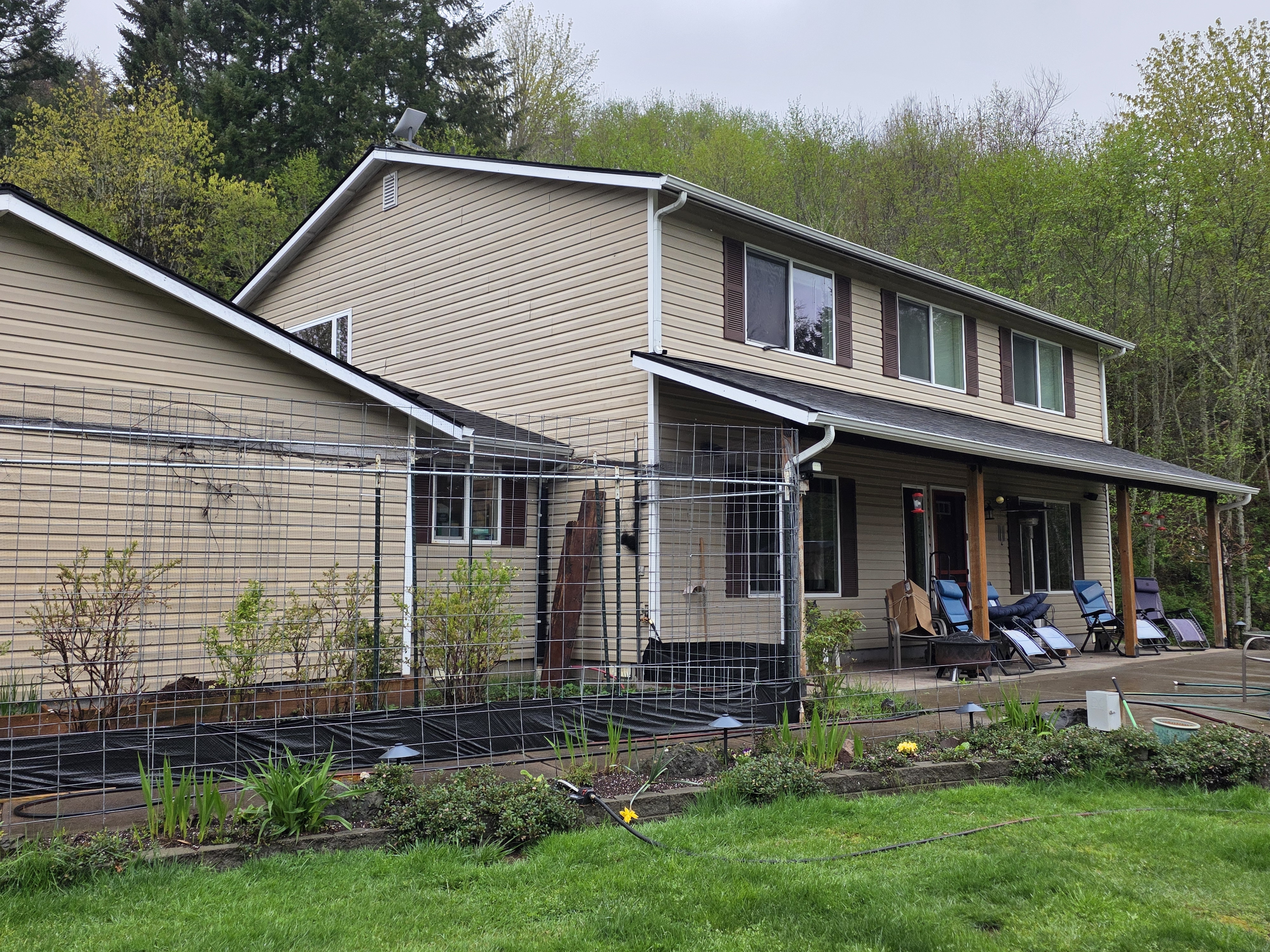 Tan lap siding and dark shutters before the siding and soffit refresh