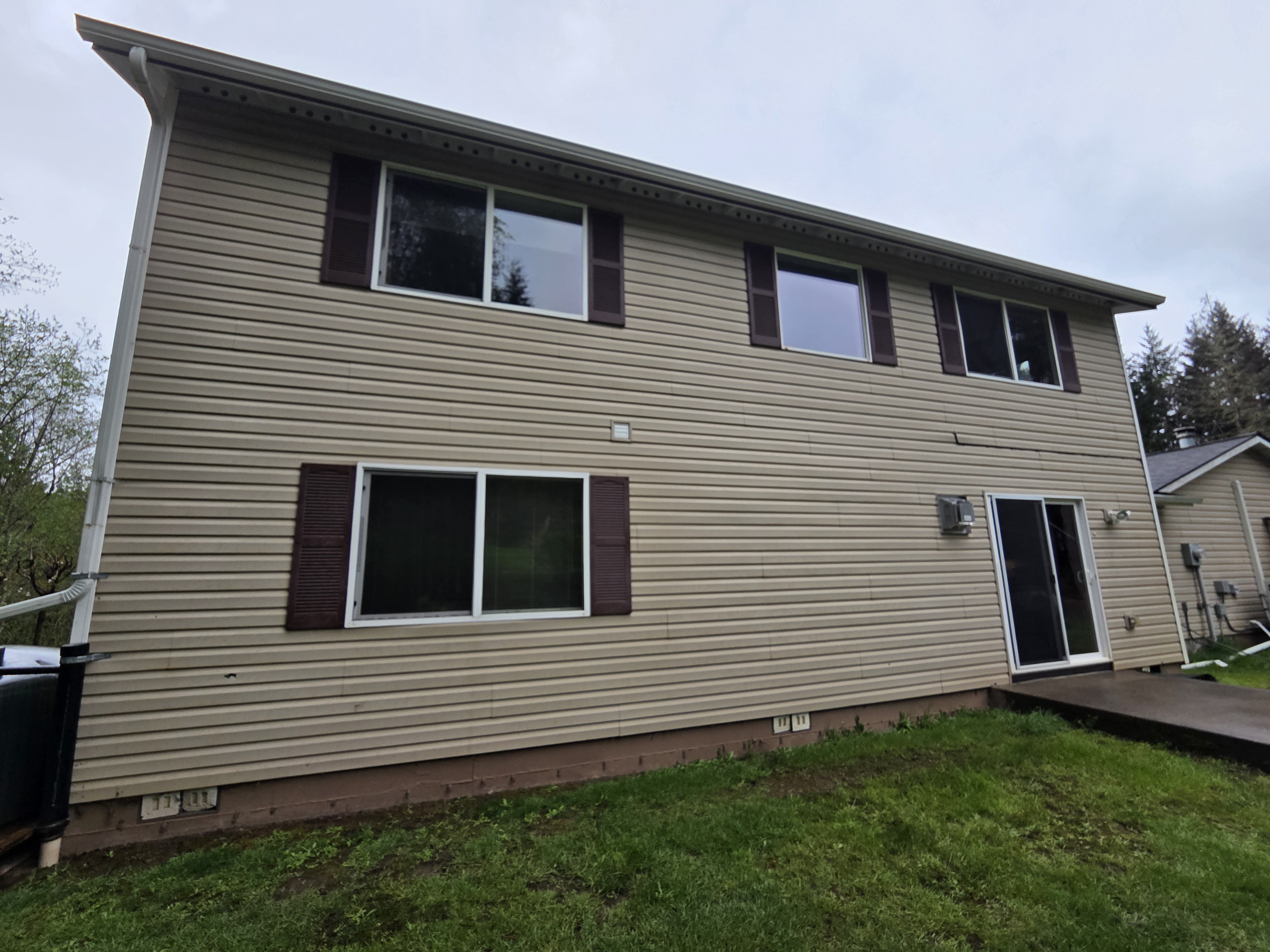 Tan lap siding and dark shutters on the rear of the house before the refresh