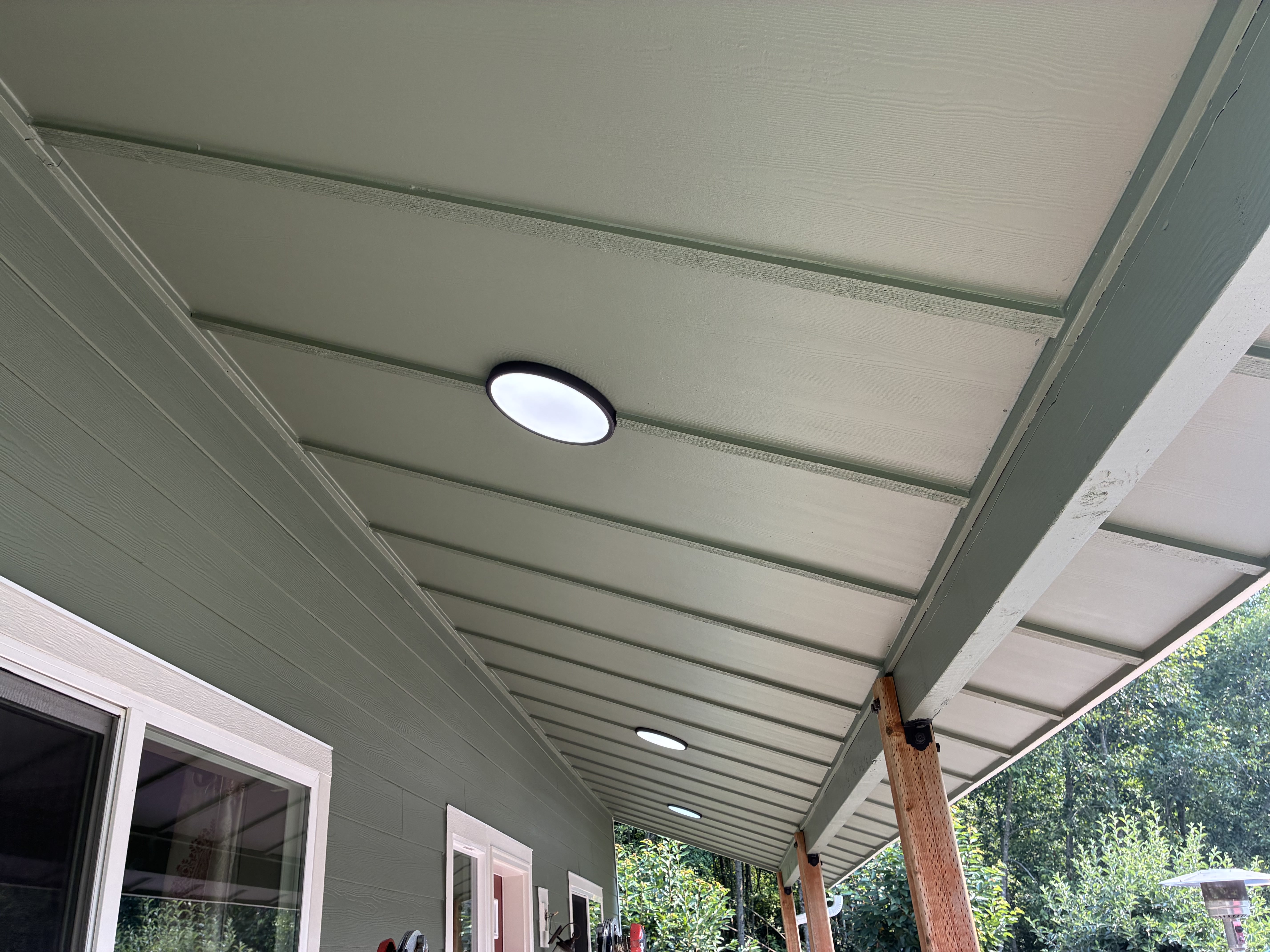 Finished sage green porch soffit with white-trimmed windows and new lights