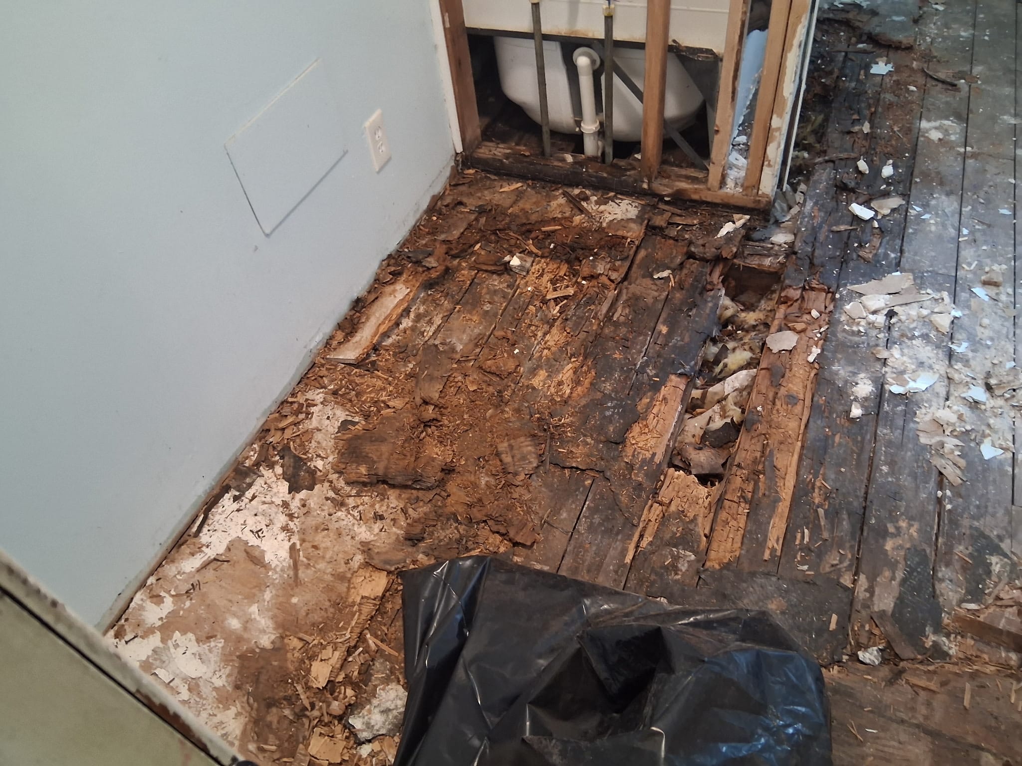 Rotted bathroom subfloor with a hole exposing insulation before repair